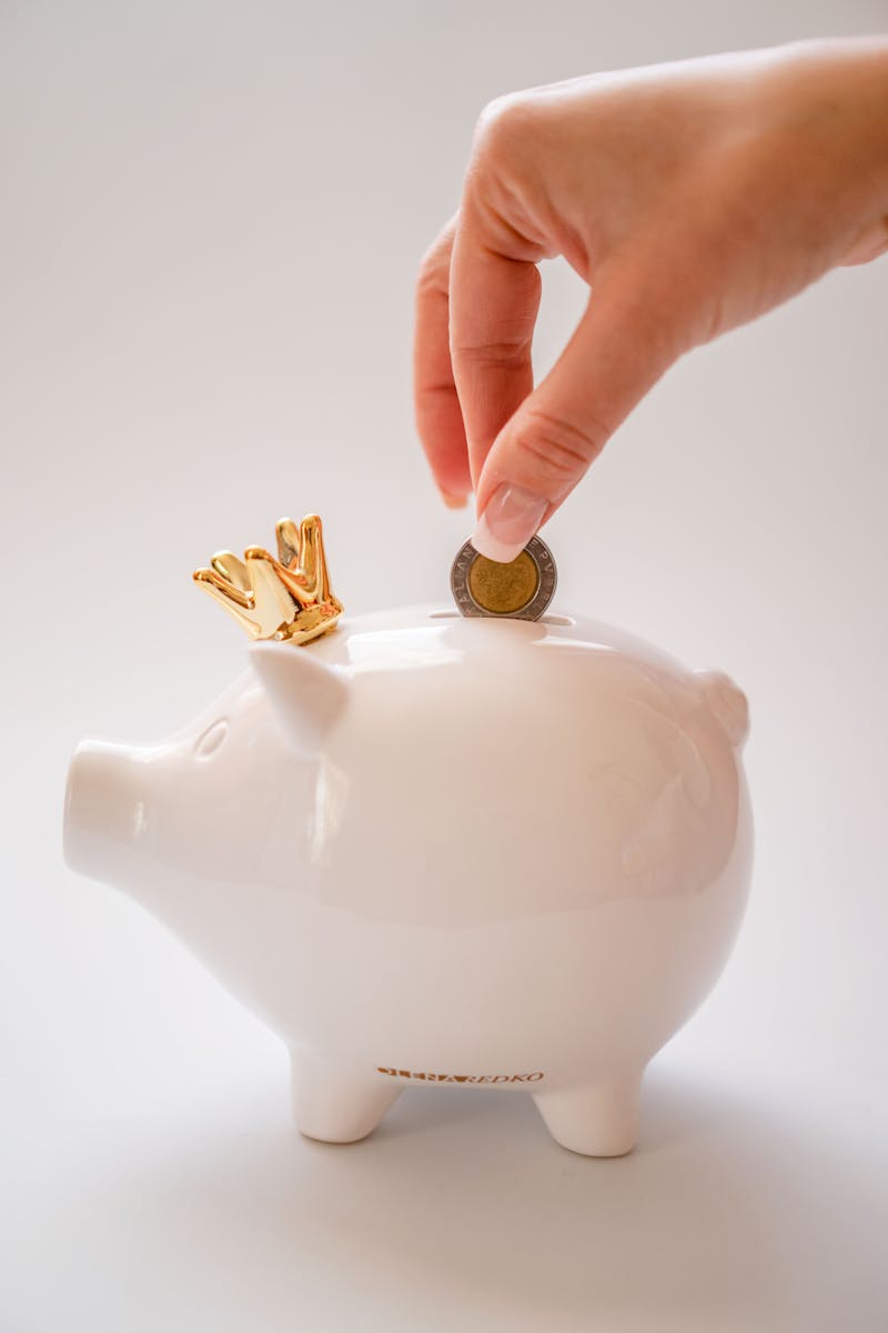 Hand Putting Coins into a Piggy Bank